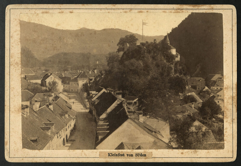 Ob svojem obisku Kamnika leta 1887, se je blejski fotograf Benedikt Lergetporer povzpel v zvonik župnijske cerkve na Šutni in od tam ujel v fotografski objektiv prehod iz predmestja Šutna v Kamnik, nad katerim se na desni strani vzpenja pobočje Malega gradu z ruševinami stražnega stolpa in kapelo v ozadju. Pet let pred nastankom posnetka, leta 1882, so na pobudo župana Maksimilijana Samca (1844-1889) znižali prehod iz Šutne v mesto na Klancu. Nastal je Samčev predor.